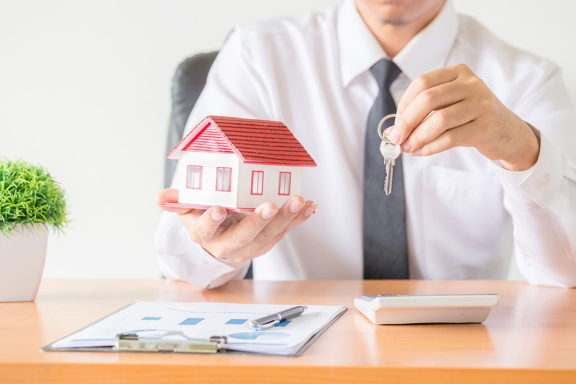 House key in home insurance broker agent’s hand protection Model house, keys exchanged, office.